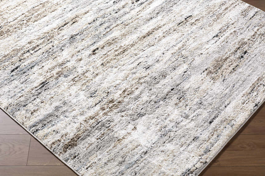 Close-up of the Aurera Area Rug. Contemporary design with black, ivory, brown, and gray abstract pattern. Corner