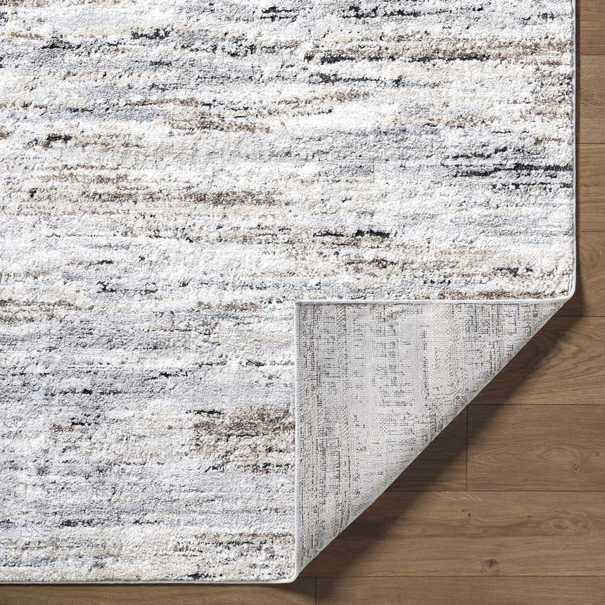 Close-up of the Aurera Area Rug showing ivory, black, and gray contemporary design and machine-woven construction. Fold