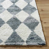 Close-up of the hand-tufted Azaria Baklava Wool Rug. Features a gray and white diamond pattern and a soft, shaggy texture. Front