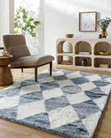 Living room scene with a gray armchair and the Azaria Baklava Wool Rug in gray and white with a diamond pattern. Roomscene-Rectangle