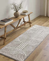 Hallway scene with Allard Charcoal Washable Area Rug runner, wood bench, vase, and books on light wood floors. Roomscene-Runner
