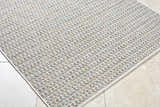 Close-up of the Ataret Ivory Area Rug, a machine-woven rug with charcoal, ivory, blue, gray, and tan tones. Corner
