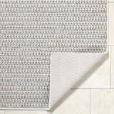 Close-up of the Ataret Ivory Area Rug showing its woven texture and colors: ivory, charcoal, blue, gray, and tan. Fold