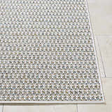 Close-up of the Ataret Ivory Area Rug. Woven texture with charcoal, ivory, sky blue, slate gray, and tan colors. Front