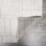 Close-up of the plush, cream Andia Grid Rug showing geometric shag design and rug backing. Fold