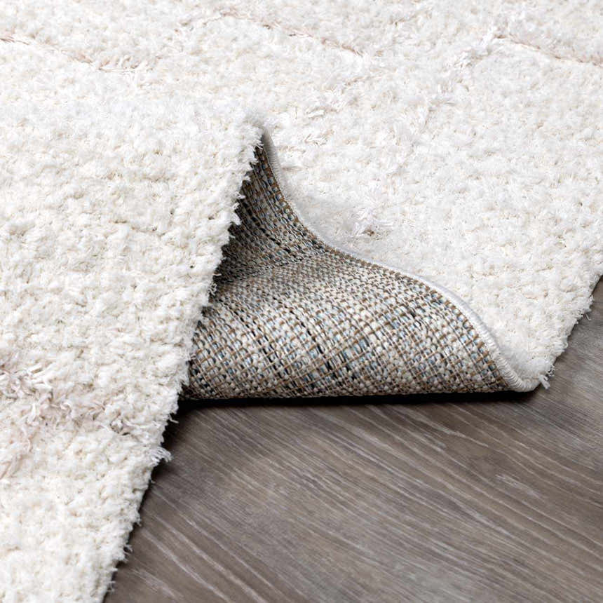 Close-up of the plush white Andia Grid Rug showing its shaggy texture and woven backing. Fold