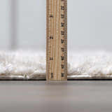 Close-up of the plush pile height of the cream Andia Plush Grid Rug with a ruler for scale. Pile