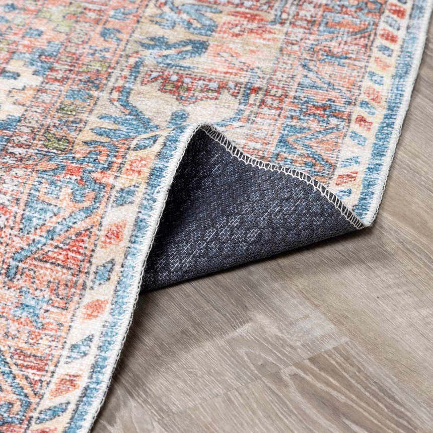 Close-up of the Holi-2300 Boutique Washable Rug showing its aqua, burnt orange, and light gray vintage-style pattern and backing. Fold
