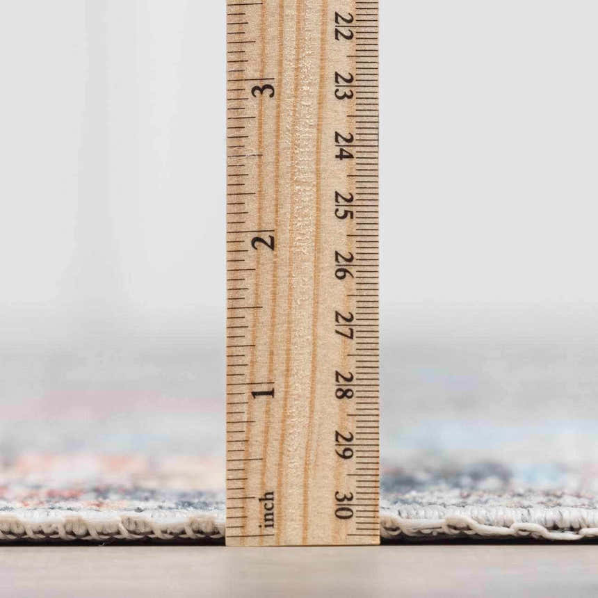 Close-up of the pile height of the Blue Burgundy Holi-2302 Washable Area Rug with a ruler showing the thickness. Pile