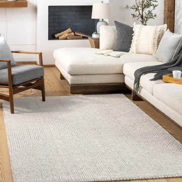 Living room scene with a cream sofa, gray chair, and Horsley Area Rug in charcoal, cream, and gray. Roomscene-Rectangle