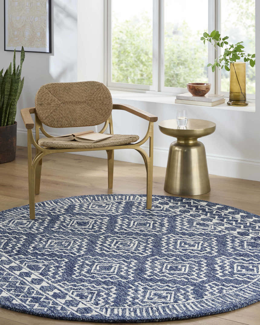 Bright room scene with a round navy and white Horton Modern Wool Rug under a woven chair and gold side table. Roomscene-Round