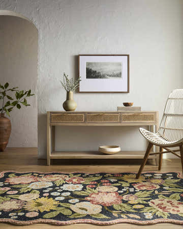 Farmhouse entry with Alodia Area Rug, wood console table, and white wicker chair. Floral rug adds color to neutral space. Roomscene-Rectangle