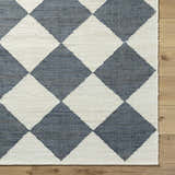 Close-up of the Andrin Gray Area Rug. Beige and steel gray jute rug with a checkered pattern and hand woven texture. Corner