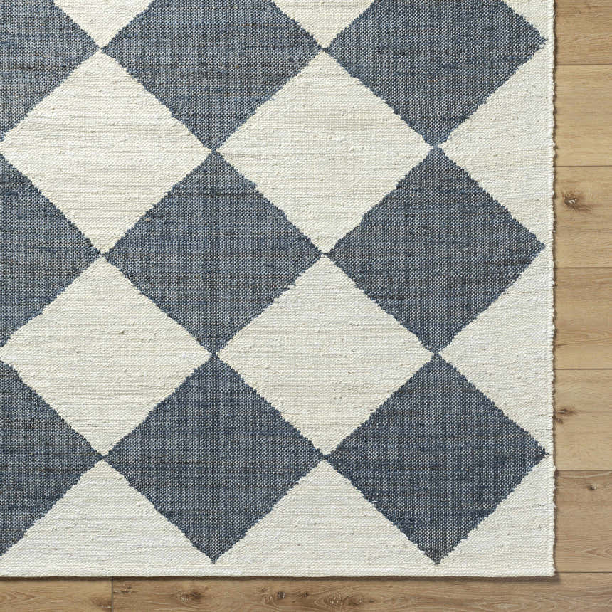 Close-up of the Andrin Gray Area Rug. Beige and steel gray jute rug with a checkered pattern and hand woven texture. Corner