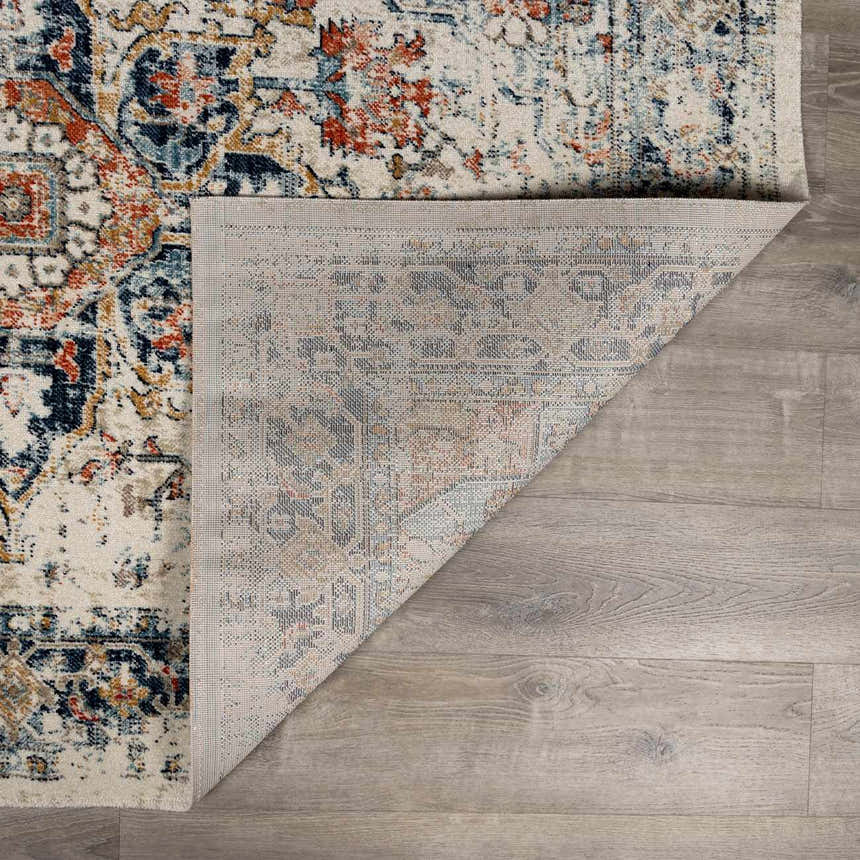 Close-up of the Dorval Traditional Rug showing its brick red, cream, and navy oriental pattern and machine-woven construction. Fold