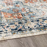 Close-up of the Dorval Traditional Rug. Features brick red, cream, denim, and navy hues in an intricate oriental pattern. Corner