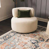 Living room scene with a cream chair on a peach, blue, and navy Dorval Traditional Rug. Roomscene-Rectangle
