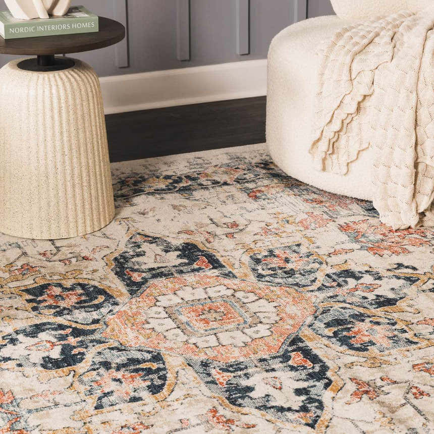 Close-up of the Dorval Traditional Rug, featuring a cream, brick red, and navy oriental pattern. Styled with a side table and ottoman. Styleshot
