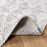 Close-up of the hand-woven New Whittington Area Rug. Gray and off-white geometric pattern with a looped, textured wool pile. Fold