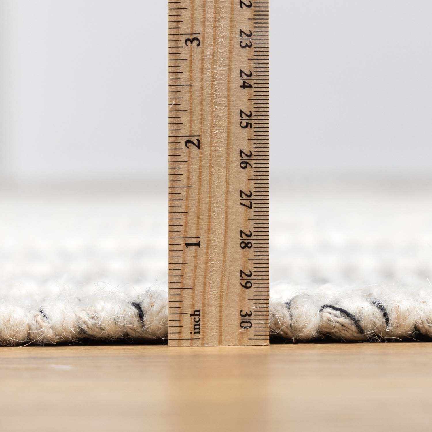 Close-up of the pile height of the hand woven New Whittington Area Rug, medium gray and off white wool. Pile