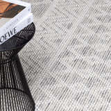 Close-up of the hand woven New Whittington Area Rug. The rug is off white and gray with a subtle geometric design. Styleshot