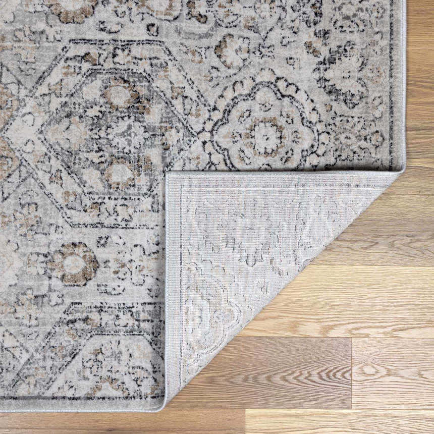Close-up of the New Parkerfield area rug. Beige, black, charcoal, and gray traditional vintage pattern. Machine woven polypropylene texture. Fold