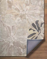 Close-up of the Ilfeld Athena Gray Floral Wool Rug showing its floral pattern, texture, and backing on a wood floor. Fold