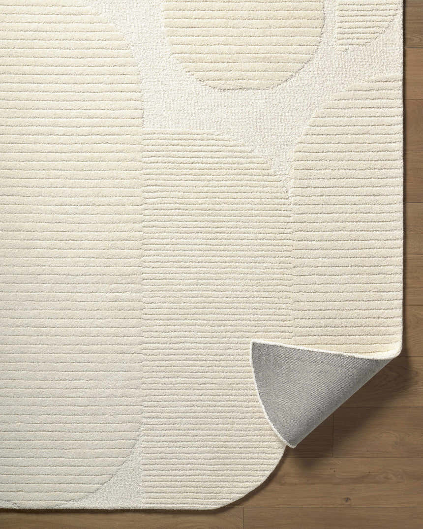 Close-up of the ivory Jgadve rug. Abstract circles and horizontal lines create a textured, contemporary design. Wool pile. Fold