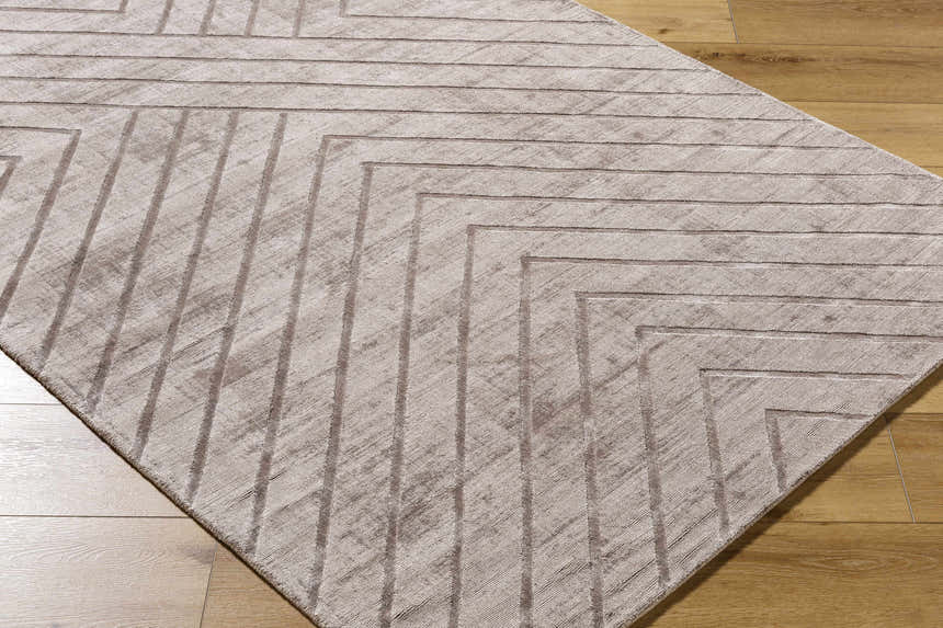 Close-up of the Tavran Taupe rug showing its subtle linear texture and geometric pattern on a wood floor. Corner