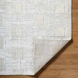 Close-up of the Jackie Area Rug featuring a cream, ivory, and white geometric pattern and machine woven texture. Fold