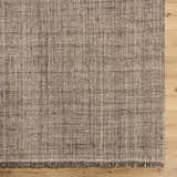 Close up of the hand woven texture and fringe of the Pufoe Modern Wool Area Rug on wood floor. Corner