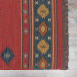 Close-up of the hand-woven Hedon Wool Area Rug. Brick red, camel, and navy colors with a Southwestern geometric pattern. Swatch