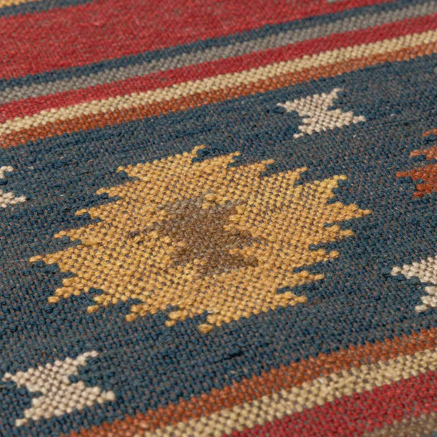 Close-up of the hand woven Hedon Wool Area Rug. Features brick red, navy, and tan colors in a Southwestern pattern. Texture