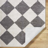 Close-up of the Arilla Diamond Checkered Washable Area Rug. Charcoal and white diamond pattern, machine woven texture. Fold