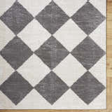 Close-up of the Arilla Diamond Checkered Washable Area Rug. Charcoal gray and white diamond pattern. Machine woven texture. Corner