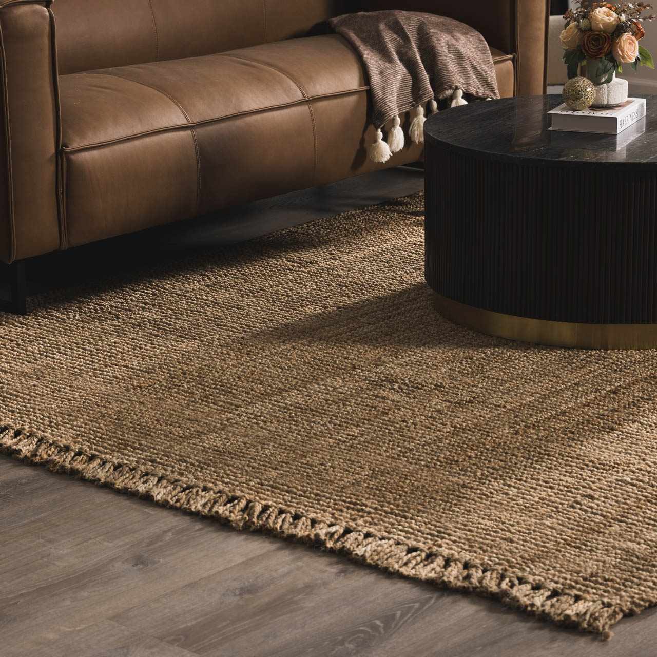 Living room scene with a brown leather sofa and the Oaks Perfect Flatweave Jute Rug in natural beige. Texture
