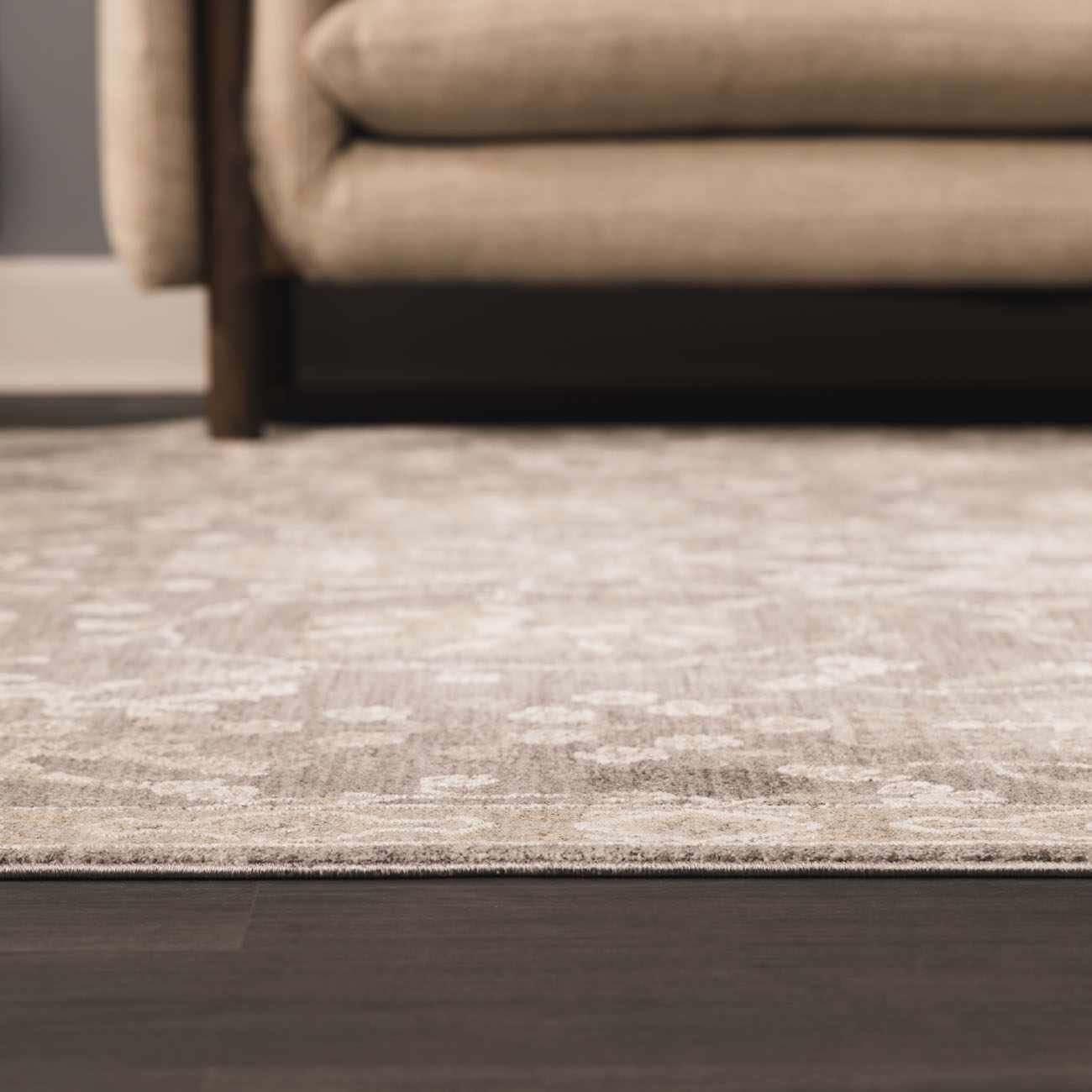 Close-up of the beige Kanimbla Thick Luxe Avant Garde Rug with a subtle traditional pattern on dark wood floors. Roomscene-Rectangle