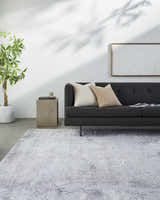 Living room scene with charcoal sofa and light gray Kapsabet Area Rug. Minimalist, contemporary style. Roomscene-Rectangle