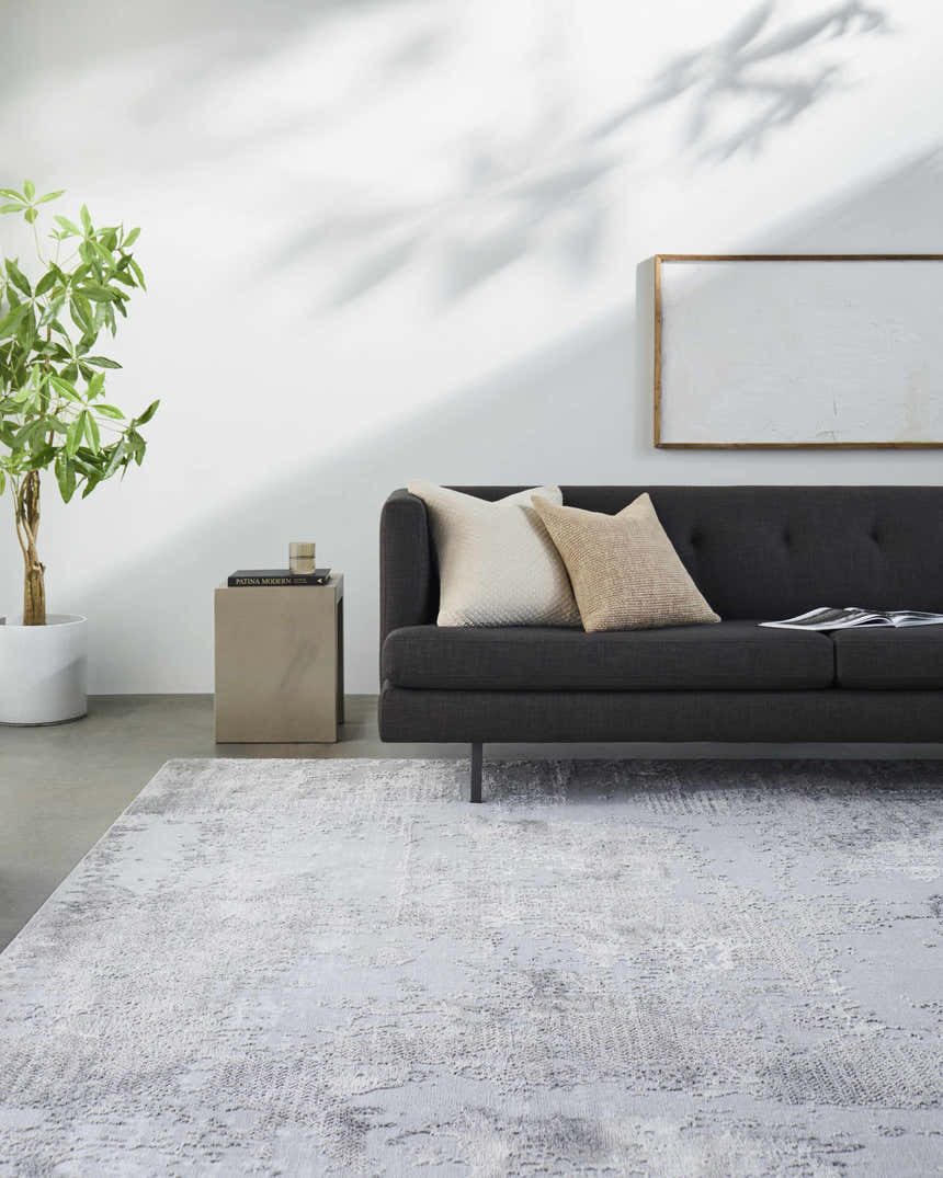 Living room scene with charcoal sofa and light gray Kapsabet Area Rug. Minimalist, contemporary style. Roomscene-Rectangle