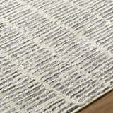 Close up of the Aricin Gray Area Rug showing its silver and gray textured, striped design. Texture