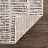 Close up of the Aricin Gray Area Rug showing light silver and gray stripes on dark wood floor. Fold