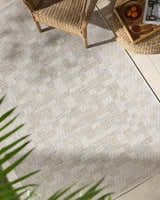 Arshad Ivory Area Rug in a bright sunroom with wicker chair and ottoman. Beige, ivory, and tan tones. Roomscene-Rectangle