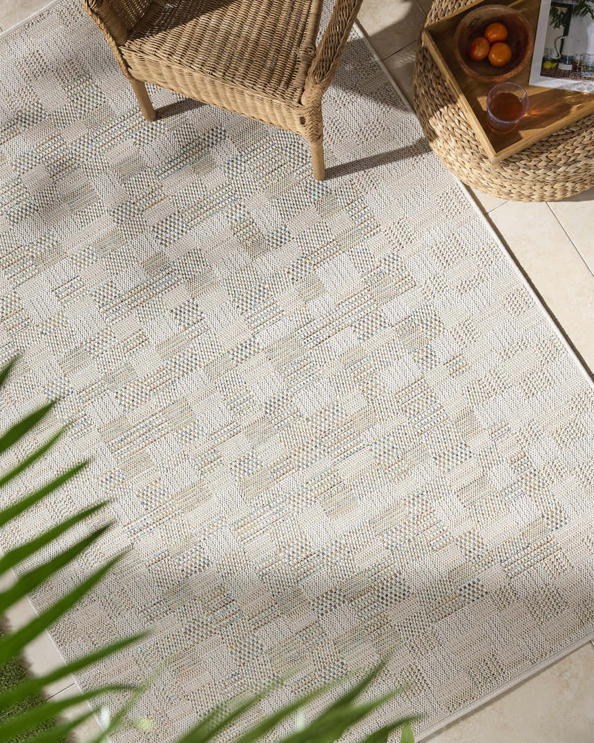 Arshad Ivory Area Rug in a bright sunroom with wicker chair and ottoman. Beige, ivory, and tan tones. Roomscene-Rectangle
