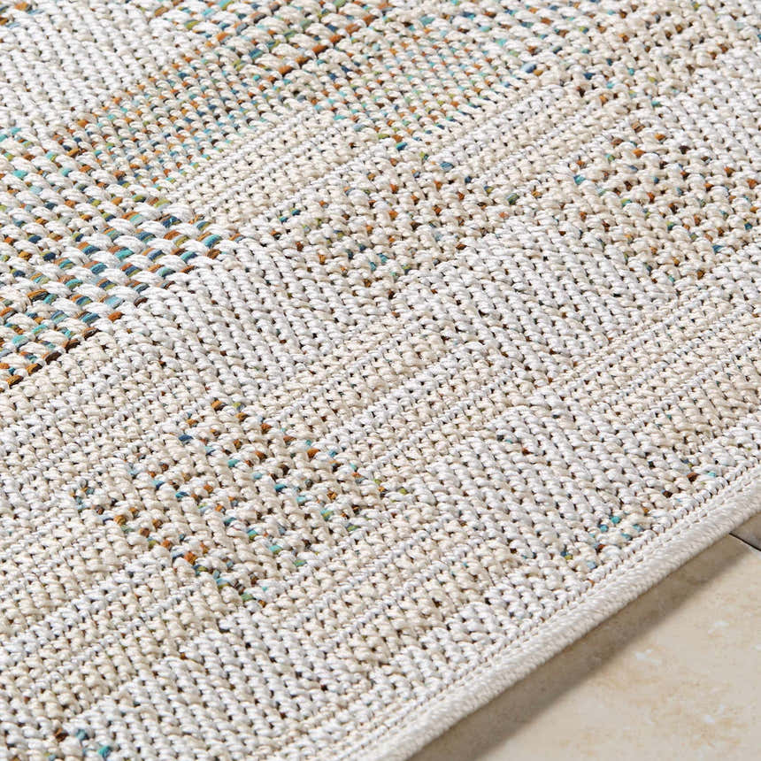 Close-up of the Arshad Ivory Area Rug showing the woven texture and beige, tan, and blue flecks of color. Texture