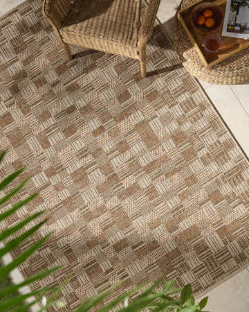 Outdoor patio scene with the Arshad Burnt Sienna Area Rug, wicker chair, and side table with drinks. Roomscene-Rectangle