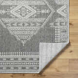 Close-up of the gray Asuman Area Rug showing the farmhouse-style white geometric pattern and polypropylene texture. Fold
