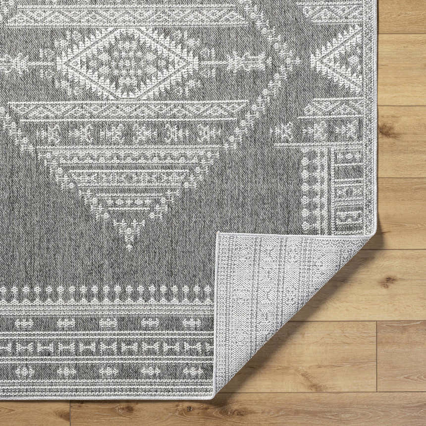 Close-up of the gray Asuman Area Rug showing the farmhouse-style white geometric pattern and polypropylene texture. Fold