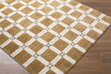 Close-up of Kalkin Light Brown Area Rug with caramel, ivory, and sage green diamond pattern on wood floor. Corner
