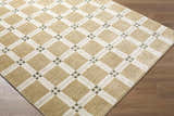 Close-up of the Kalkin Tan Area Rug featuring a tan and white diamond pattern with small green accents. Corner
