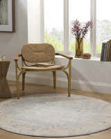 Light-filled room with a round Kofi Thick Luxe Area Rug, woven chair, and natural wood accents. Roomscene-Round